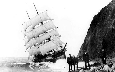 Under almost full sail, the doomed Glenesslin grinds against the side of Neahkahnie Mountain as its crew members pose for the camera.